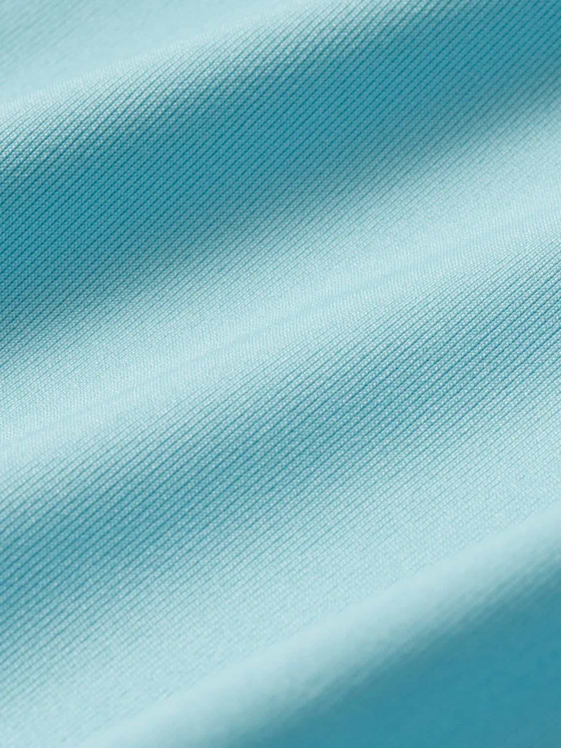 Aqua rashguard fabric with ribbed texture and diagonal folds showing the material's stretch quality.