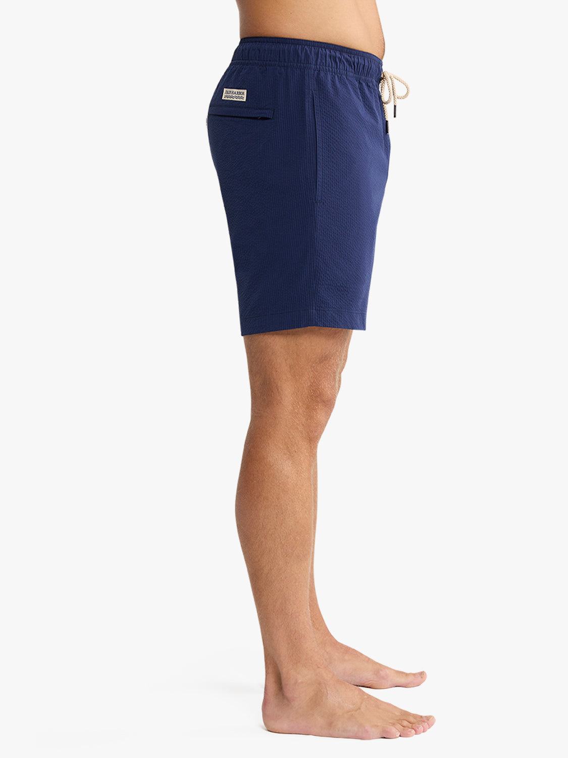 Navy seersucker swim trunk with elastic waistband, drawstring, and side pocket on model.