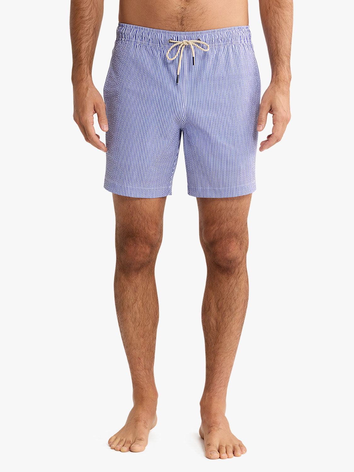 Man wearing light blue seersucker swim trunks with vertical stripe pattern and drawstring waist.