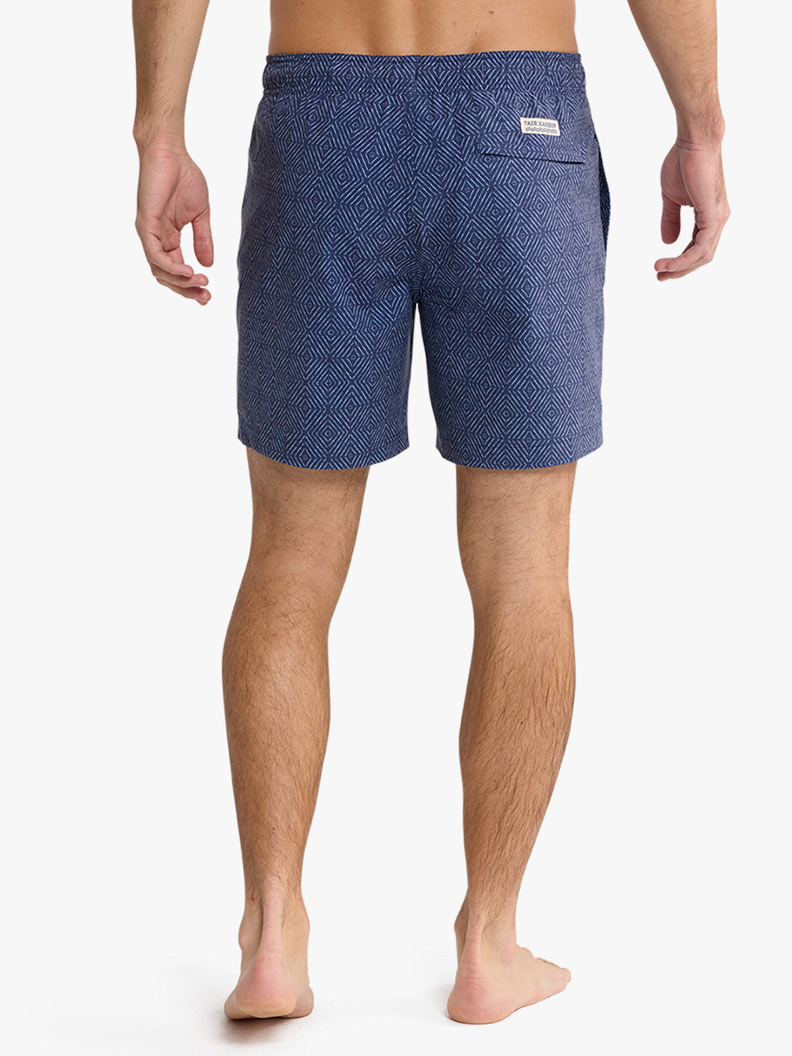 Man wearing navy shibori patterned swim trunk with geometric diamond print design.