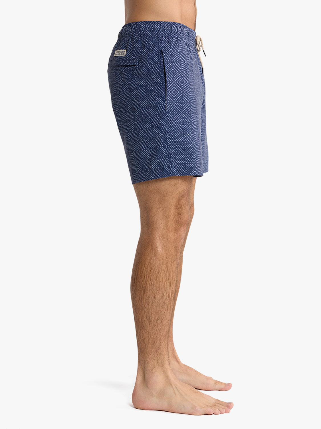 Man wearing navy shibori patterned swim trunk with diamond geometric design and drawstring.
