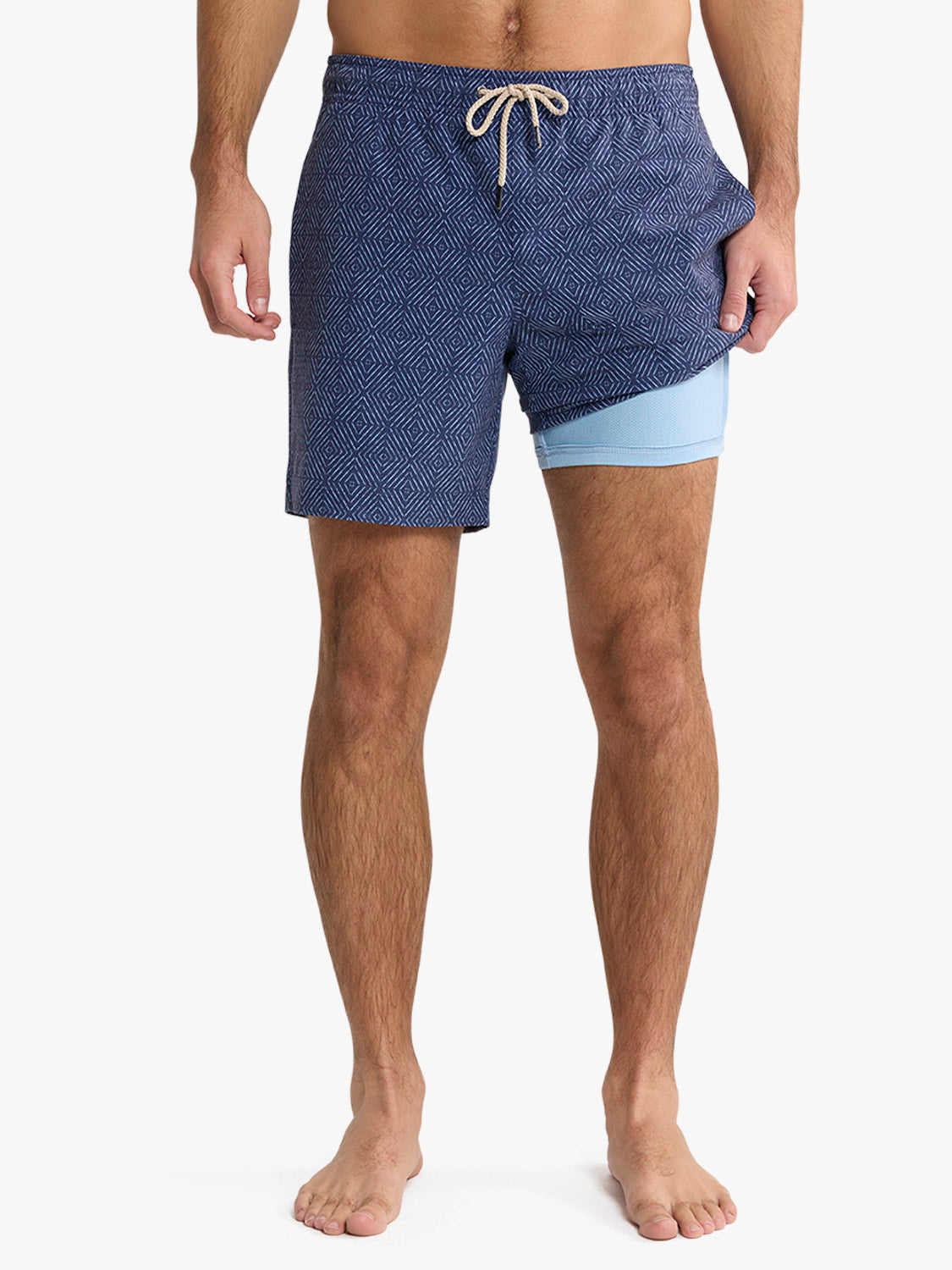 Man wearing navy shibori patterned swim trunks with light blue liner shorts and drawstring waist.