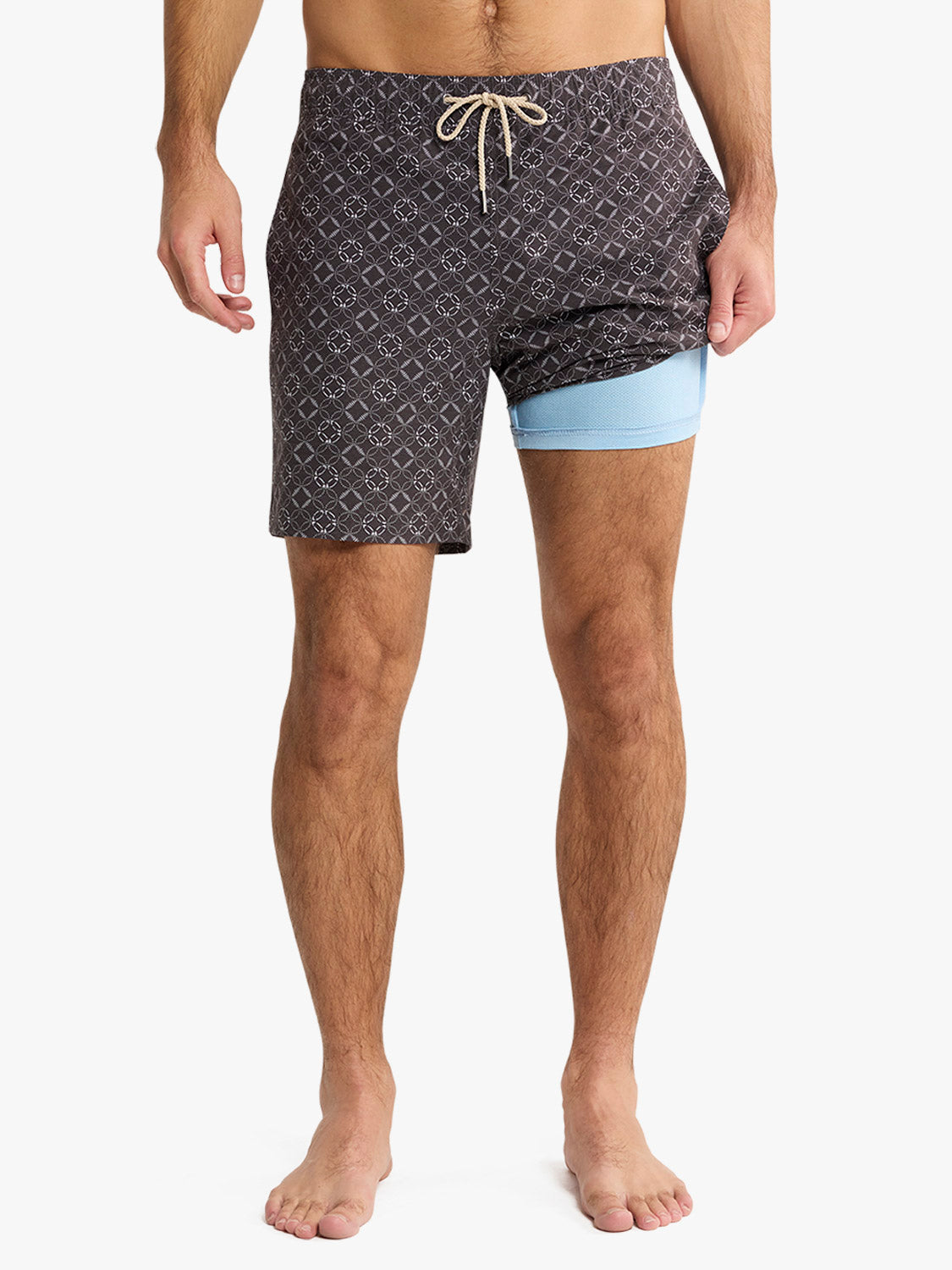 Men's swim trunks with charcoal geometric pattern and light blue compression shorts underneath.