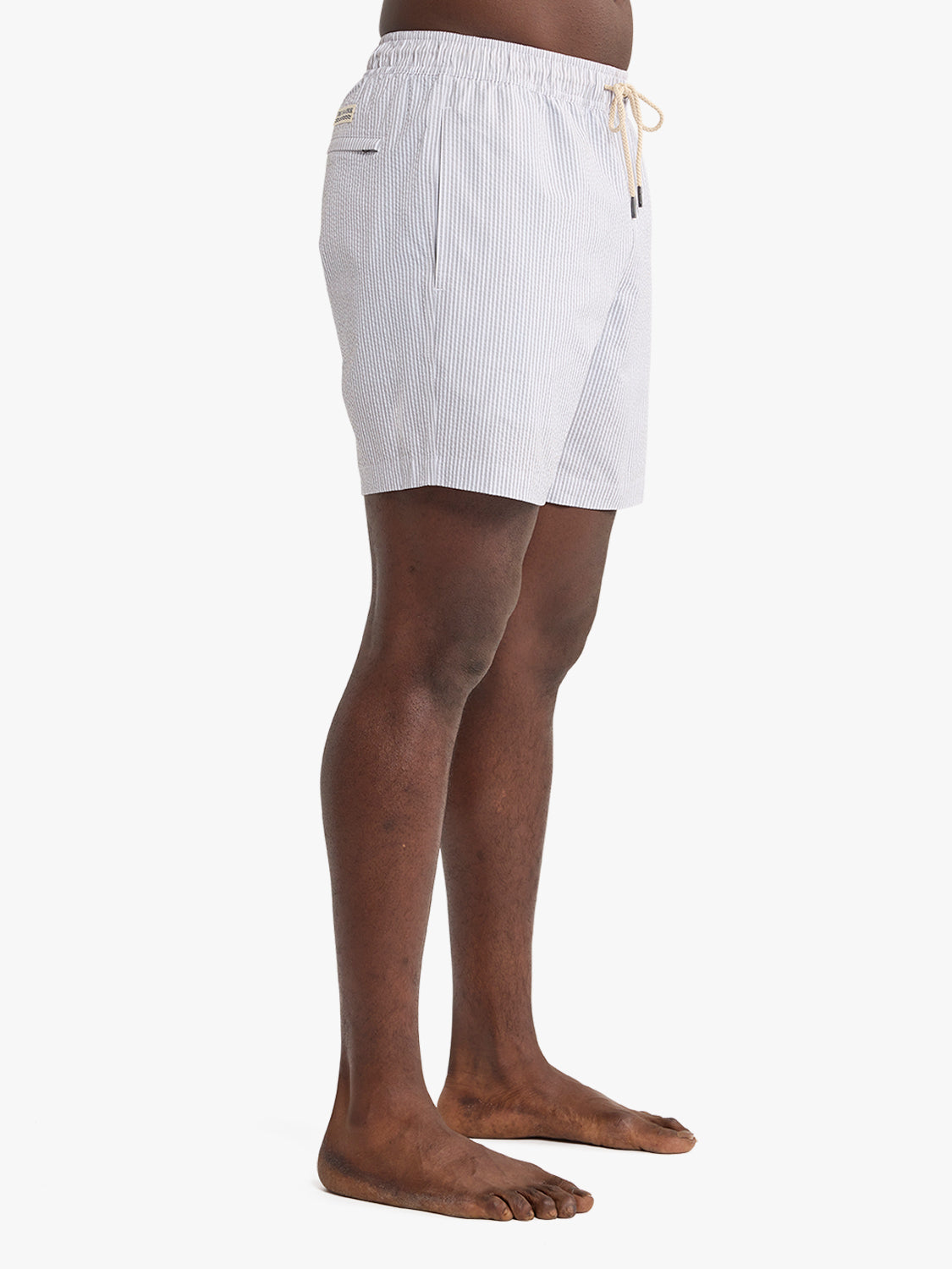 Grey seersucker swim trunks with vertical striped texture and drawstring waist closure.