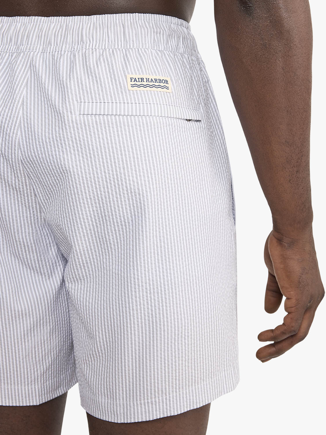 Grey seersucker swim trunk with vertical stripe texture and Fair Harbor brand label on back pocket.