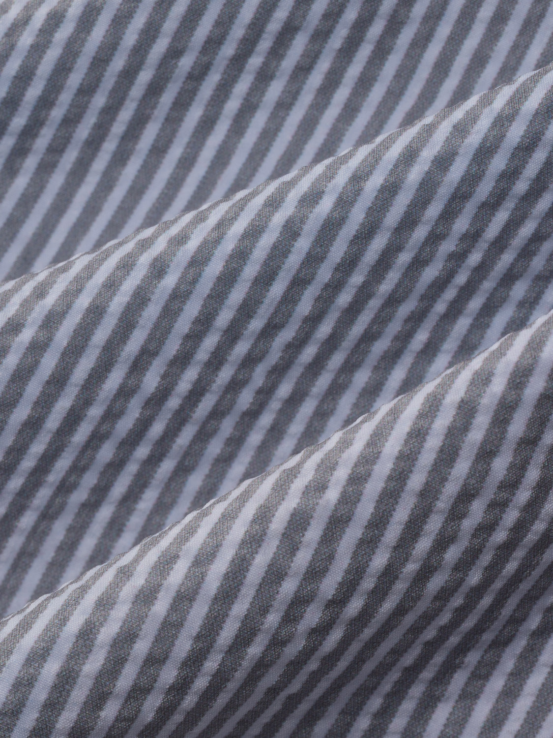 Grey seersucker fabric with alternating light and dark vertical stripes and textured surface detail.