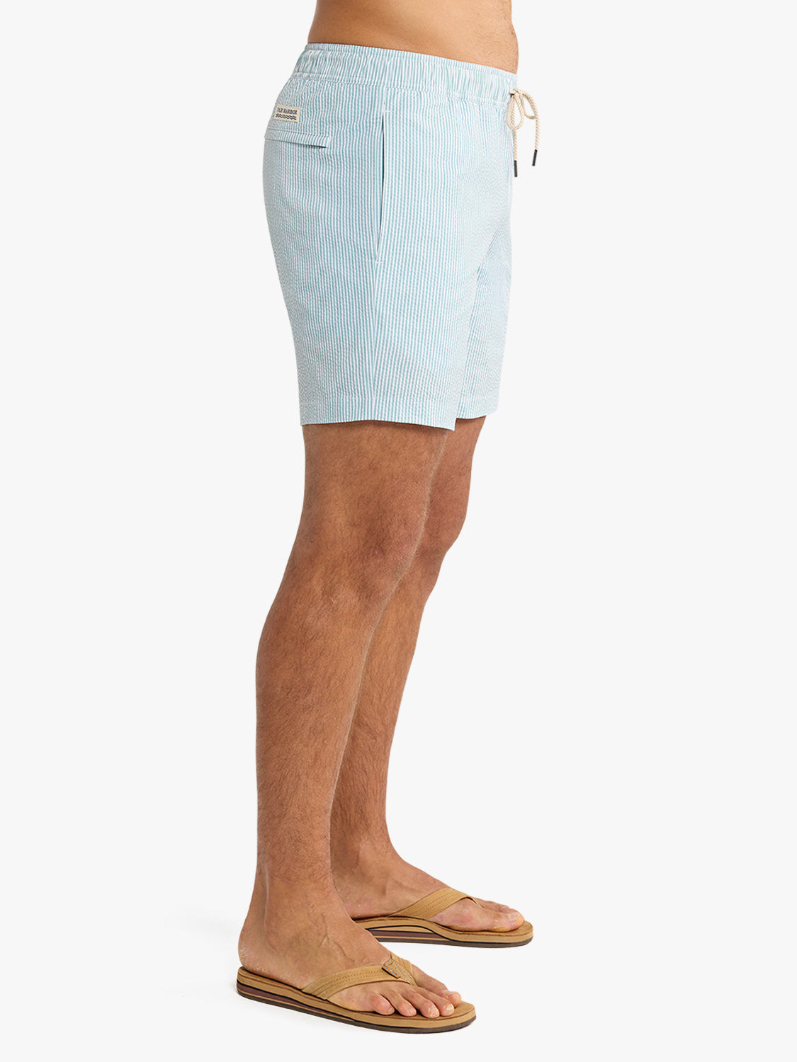 Light blue seersucker swim trunk with vertical stripes and drawstring waist displayed on a model.