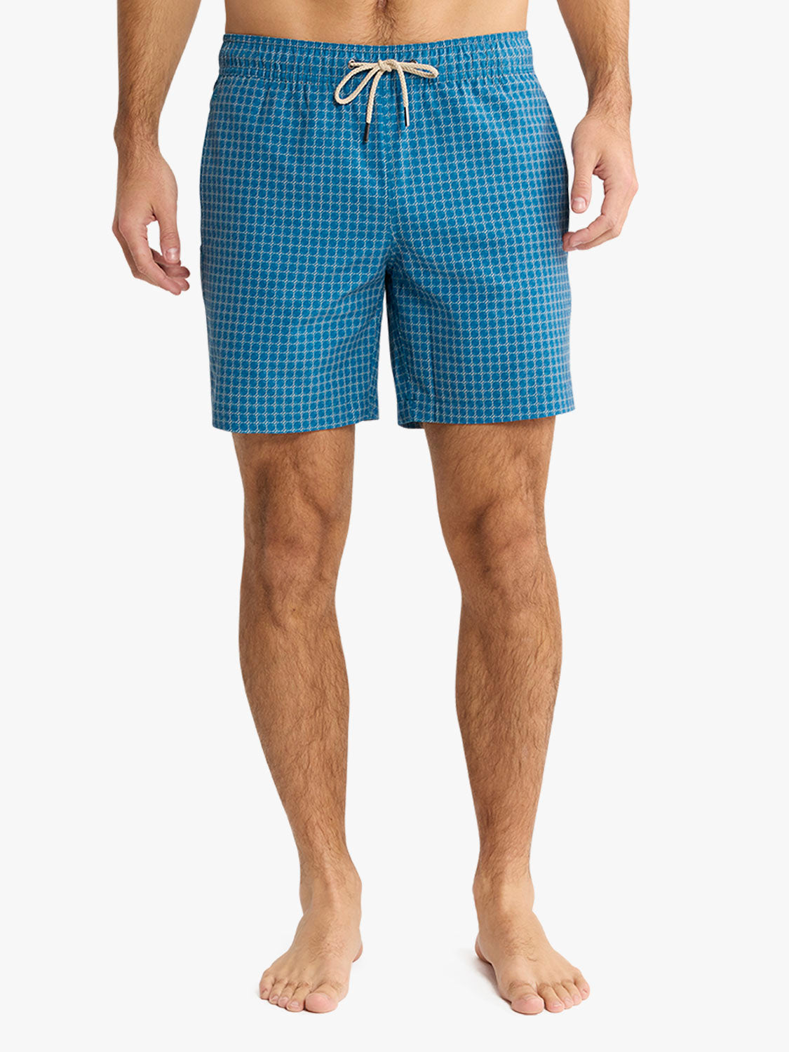 Man wearing teal swim trunks with geometric grid pattern and drawstring waistband.