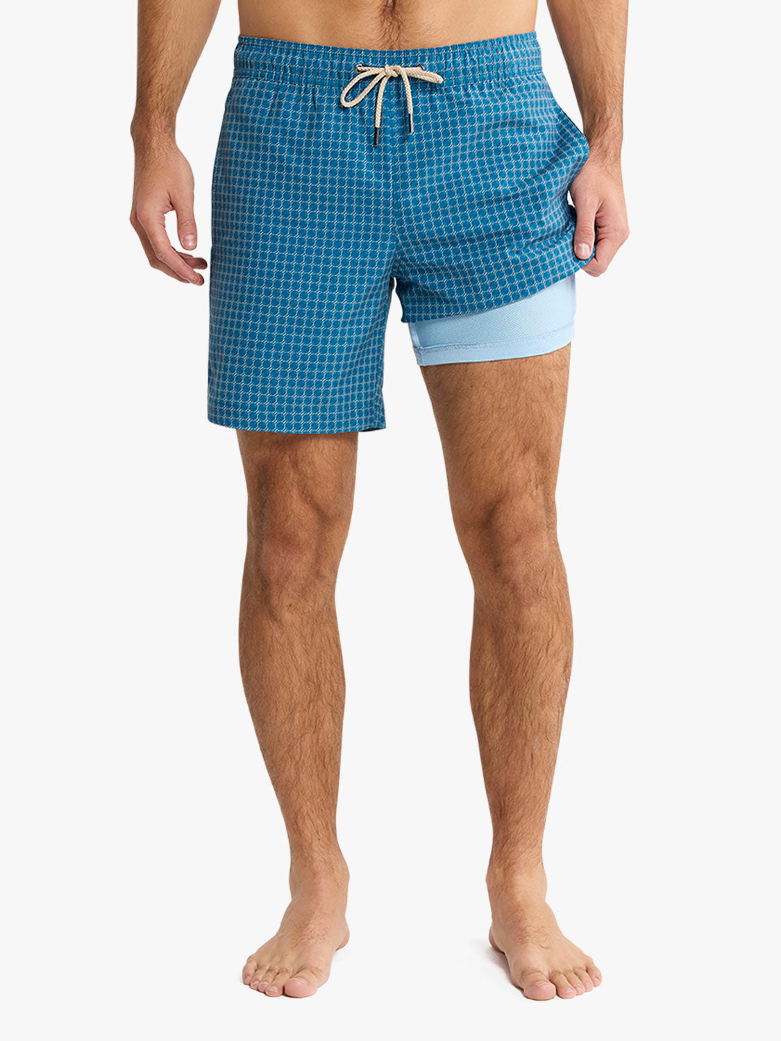 Man wearing teal geometric patterned swim shorts with light blue liner and drawstring waist.