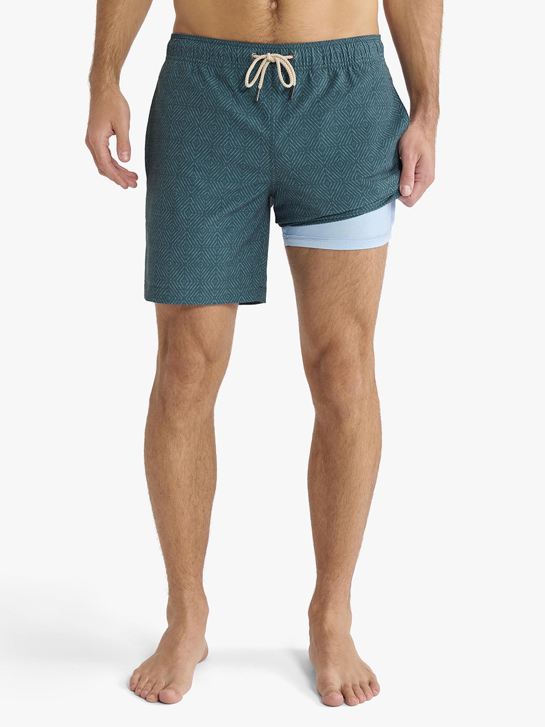 Men's swim trunks in teal with geometric shibori pattern and light blue liner shorts.