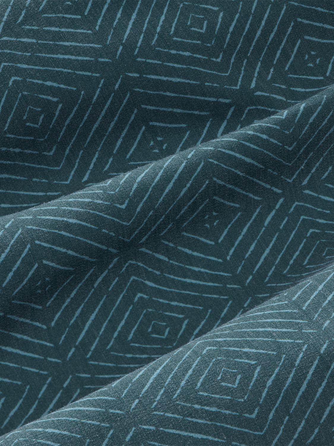 Green fabric with geometric shibori pattern featuring nested diamond and linear designs in varying shades.