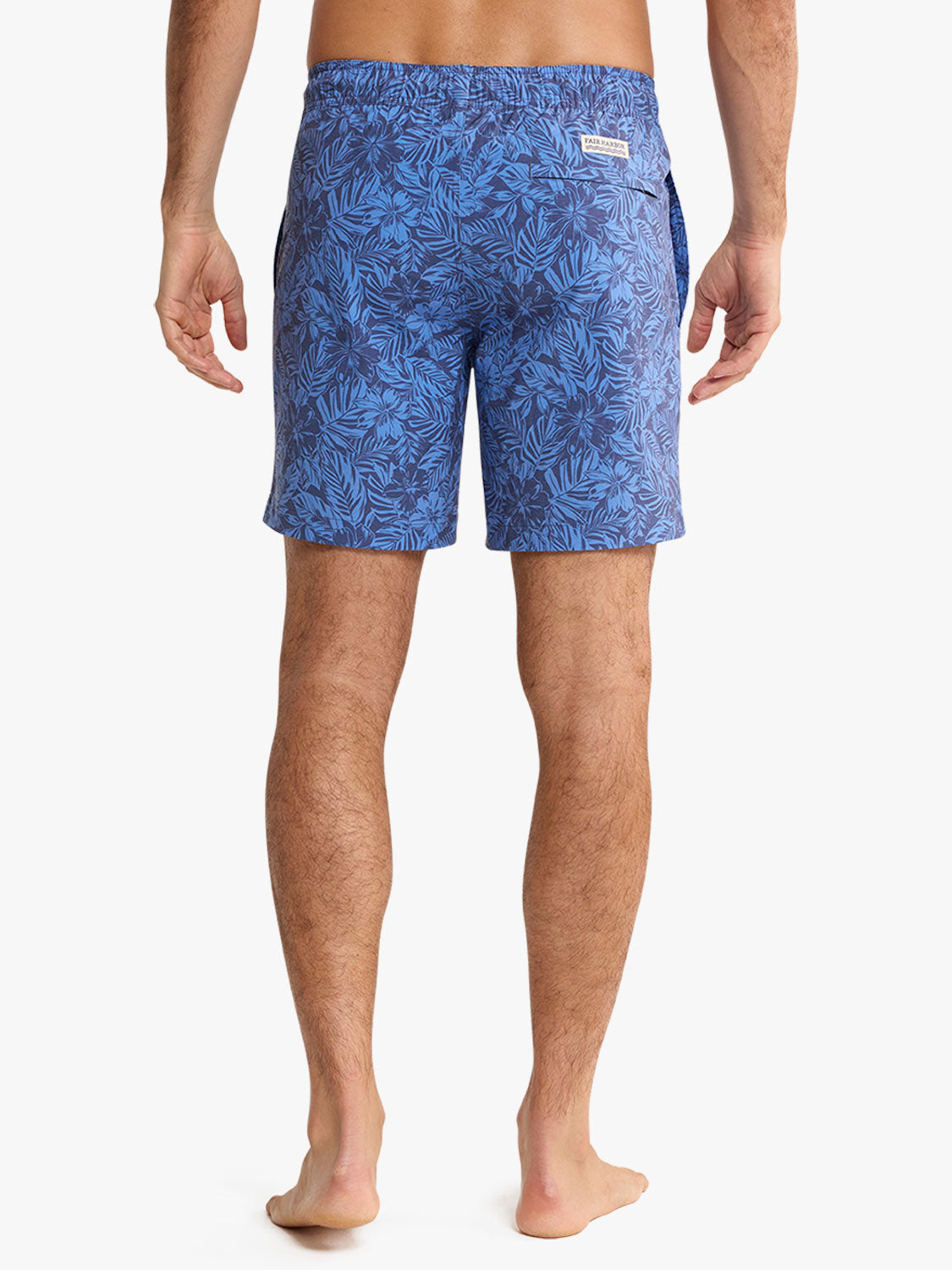 Men's swim trunk in island blue with dense leaf pattern all over shown from back view.