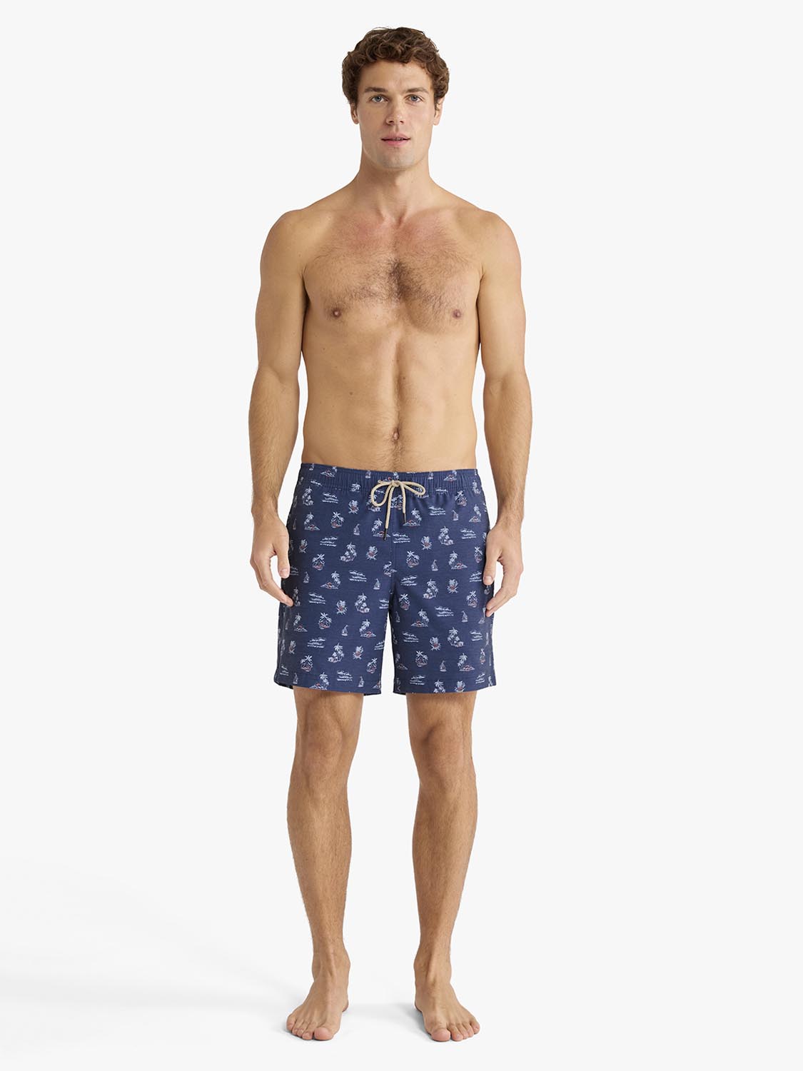 Man wearing navy swim trunks with small nautical pattern and drawstring waist.