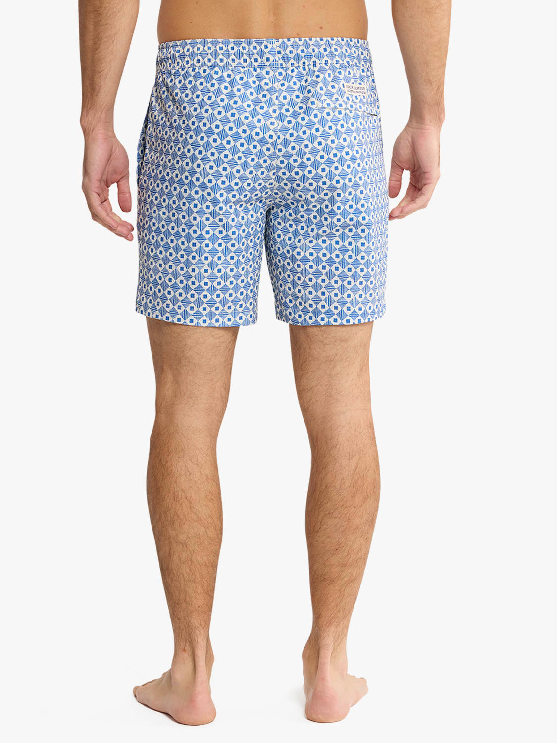 Man wearing blue and white geometric patterned seersucker swim shorts viewed from behind.