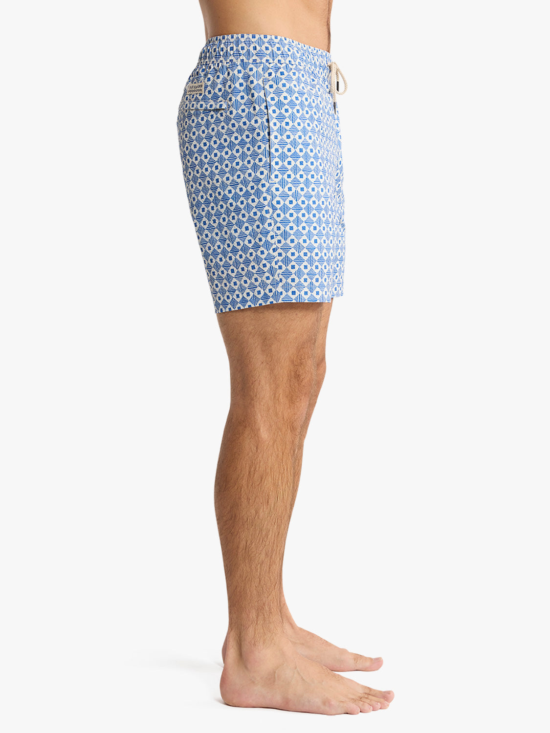 Man wearing blue and white geometric patterned swim trunks with drawstring waistband.