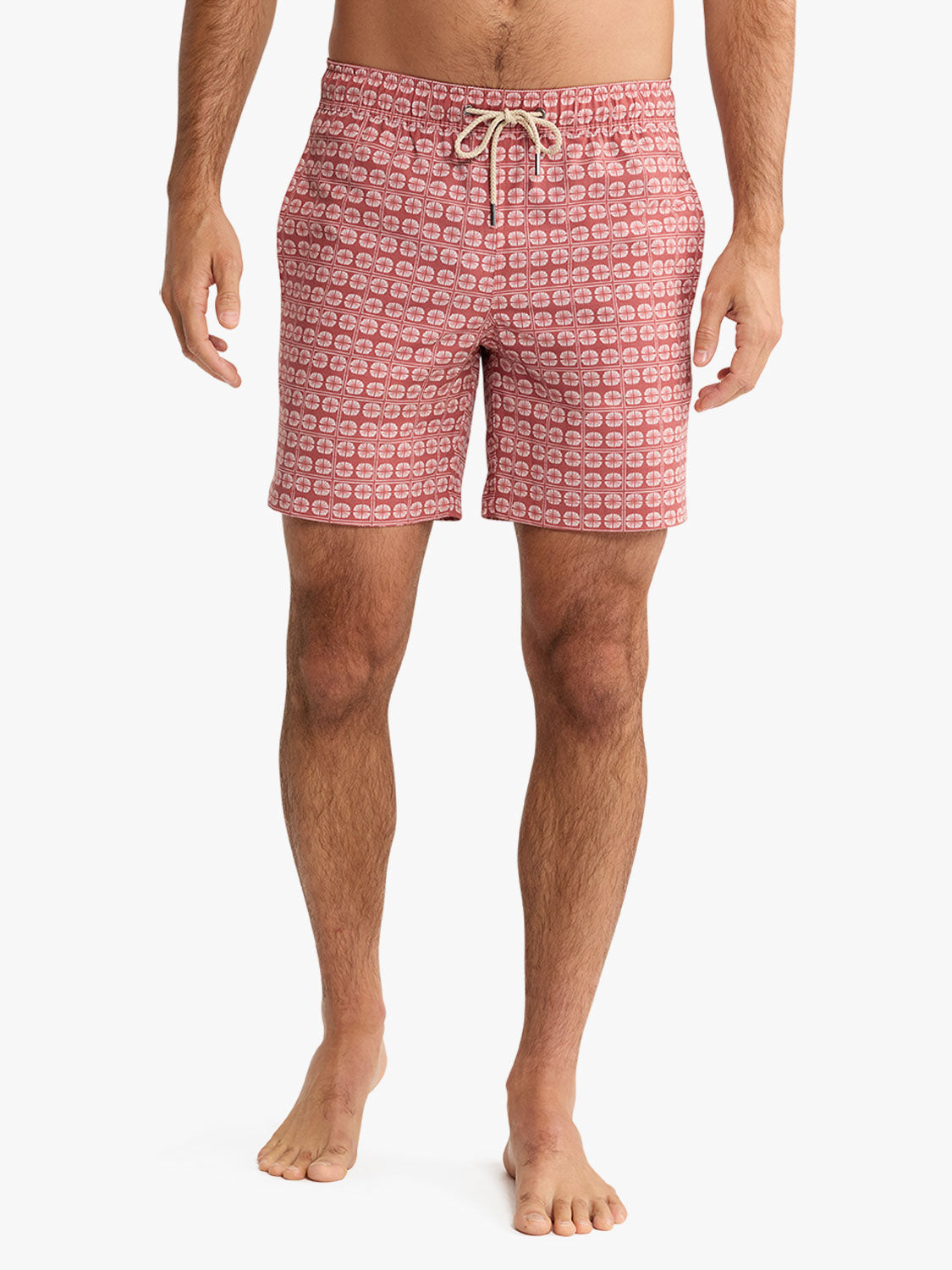 Man wearing redstone pink swim trunk with geometric sand dollar pattern and drawstring waistband.