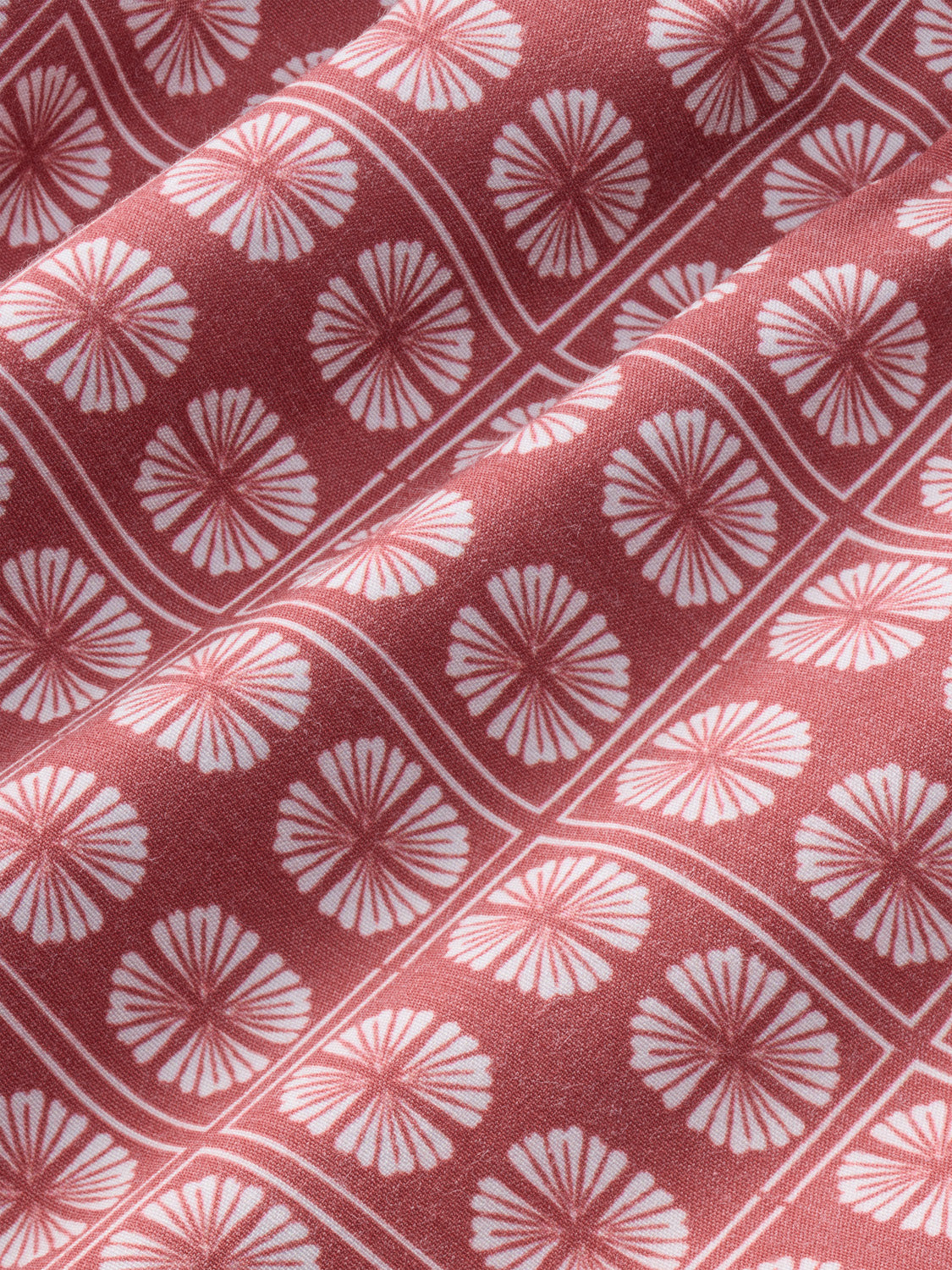 Redstone and sand dollar fabric features repeating fan-shaped floral motifs in pink and white.