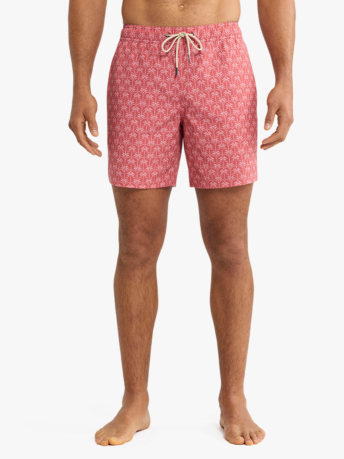 Man wearing red swim trunks with a geometric palm leaf pattern and drawstring waistband.