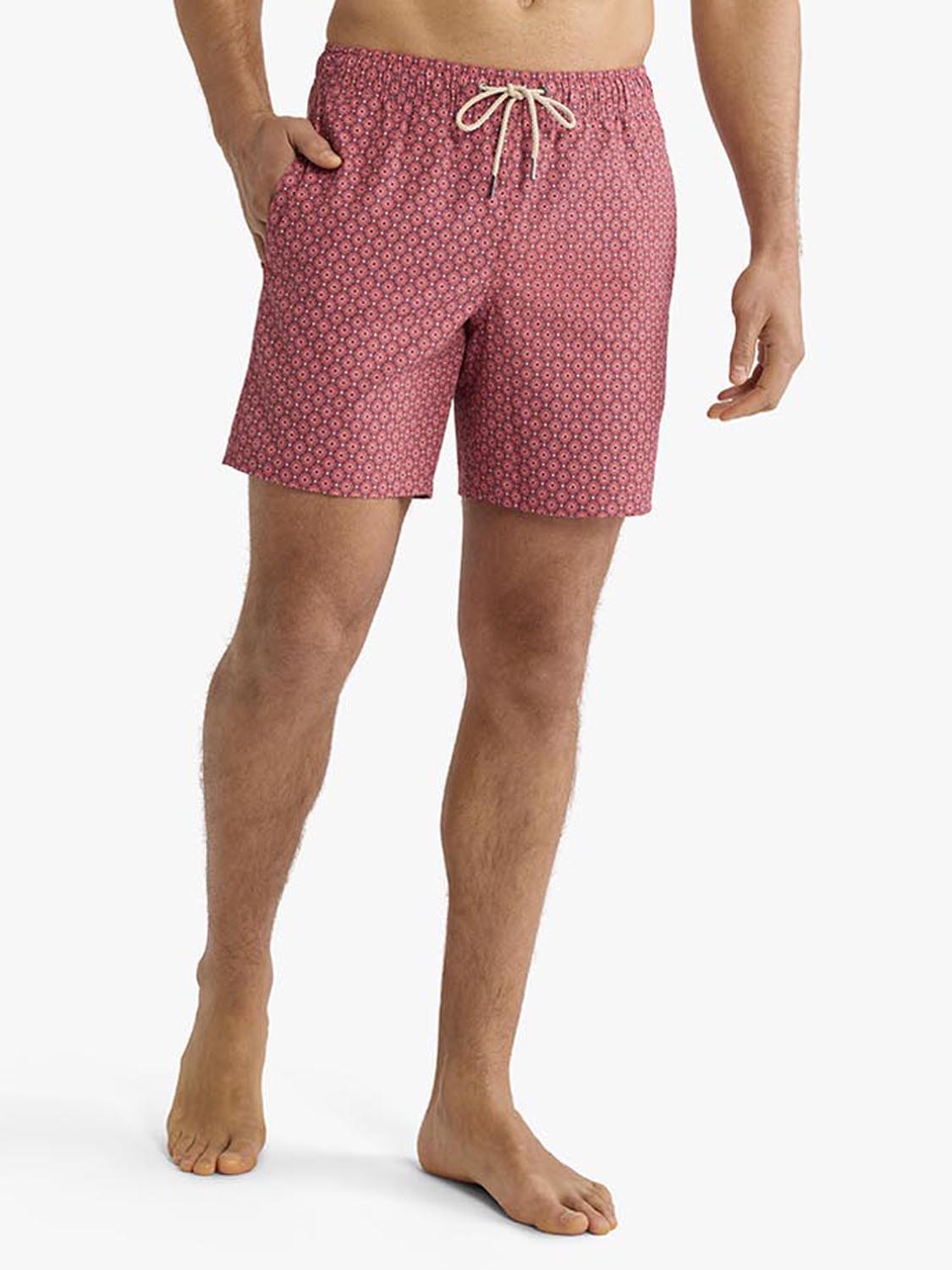 Man wearing red bandana geo patterned swim trunk with drawstring waistband standing barefoot.