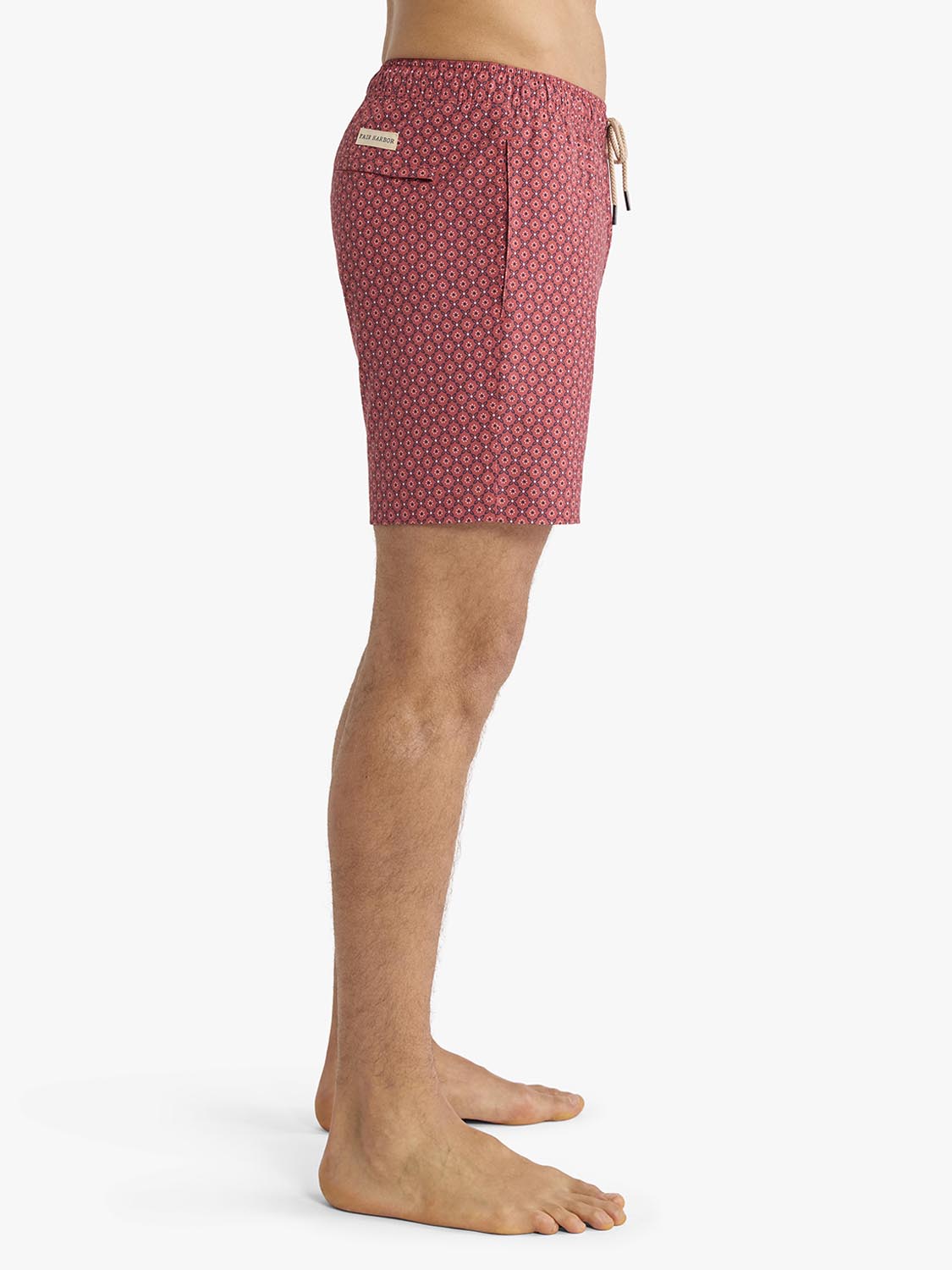 Man wearing red swim trunks with small geometric bandana pattern and drawstring waistband.