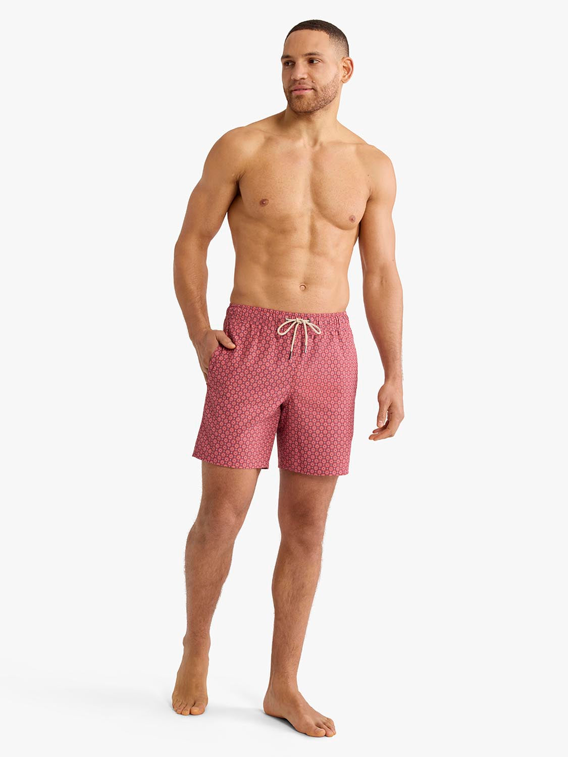 Man wearing red bandana geo patterned swim trunk shorts with drawstring waistband.