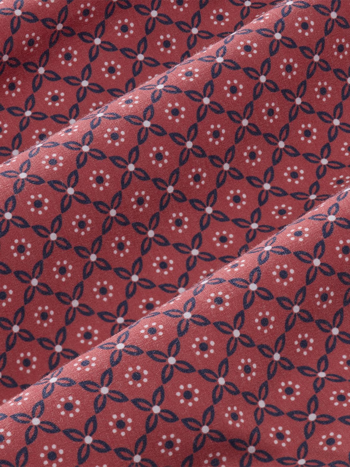 Red fabric with navy blue geometric floral pattern and white dotted accents throughout.