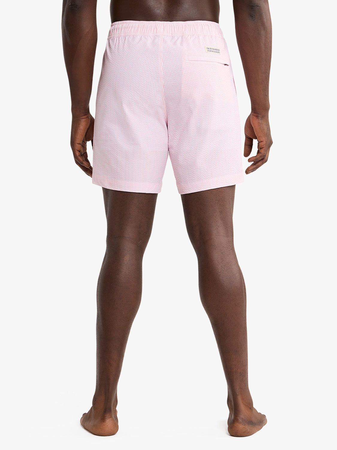 Man wearing pink seersucker swim trunk with textured fabric and back pocket detail.