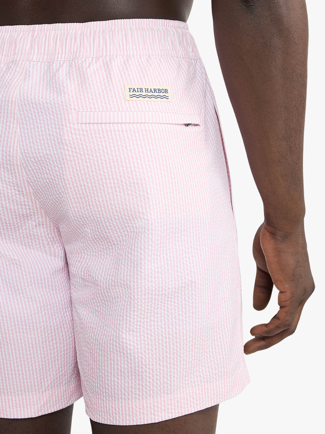 Pink and white striped seersucker swim trunk with Fair Harbor logo on back pocket.