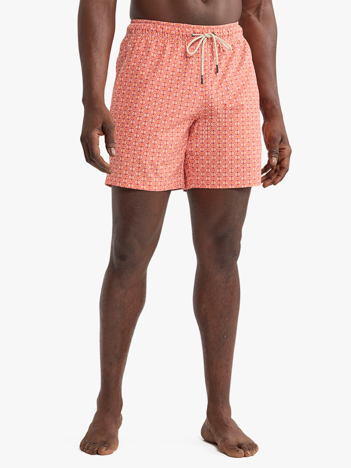 Man wearing tangerine swim trunk with small geometric pattern and drawstring waist.