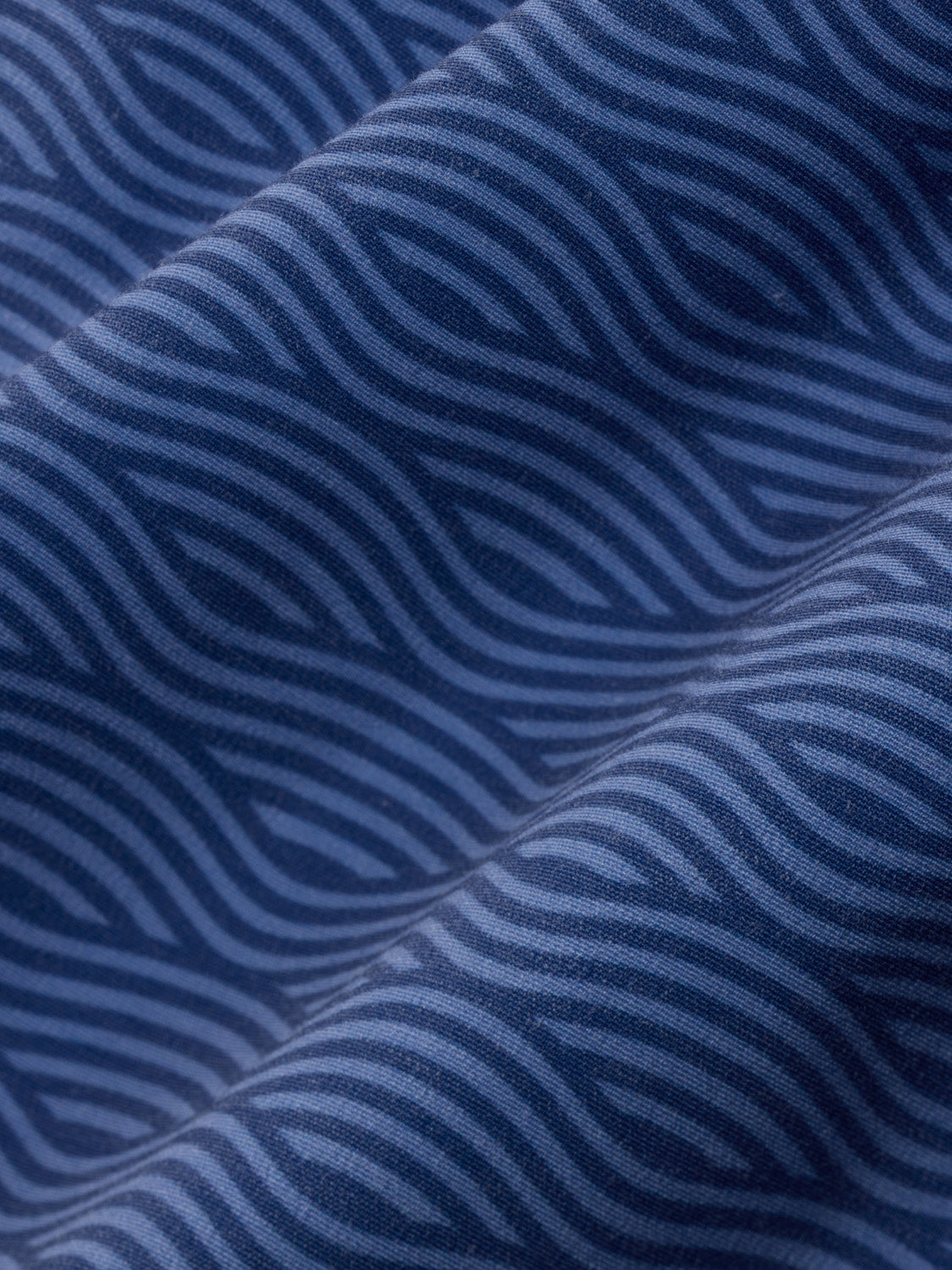 Blue fabric with wavy striped pattern showing gathered texture and folds in detail.