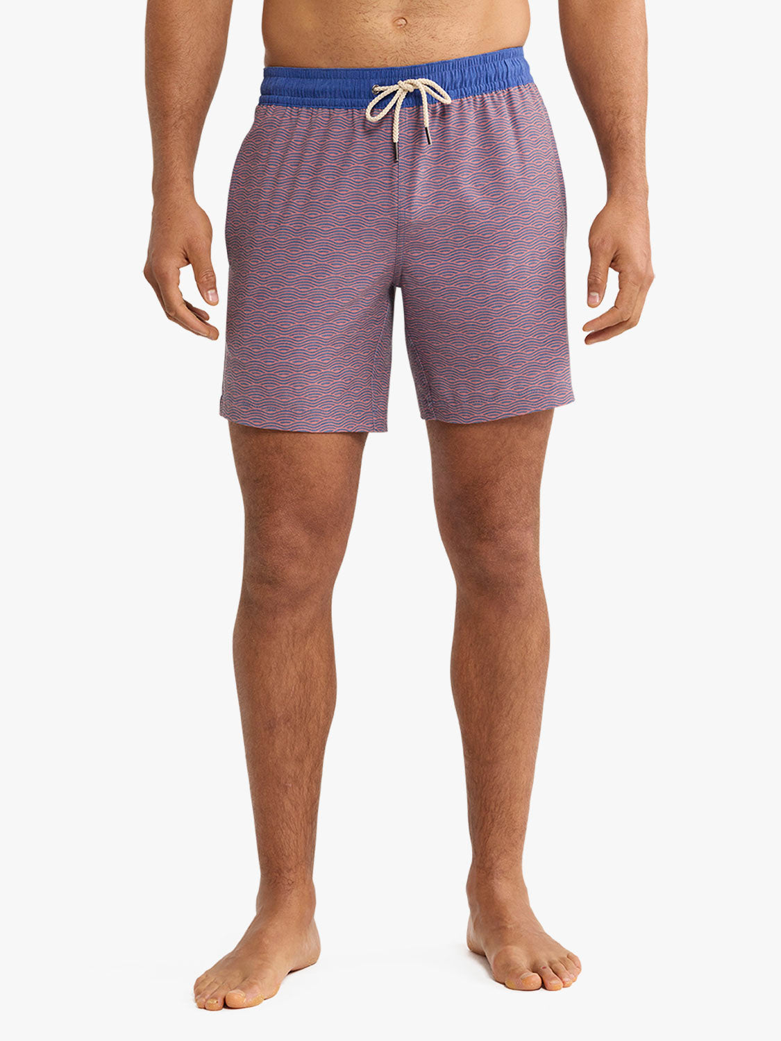 Man wearing red and blue striped swim trunks with a drawstring waistband and blue elastic trim.