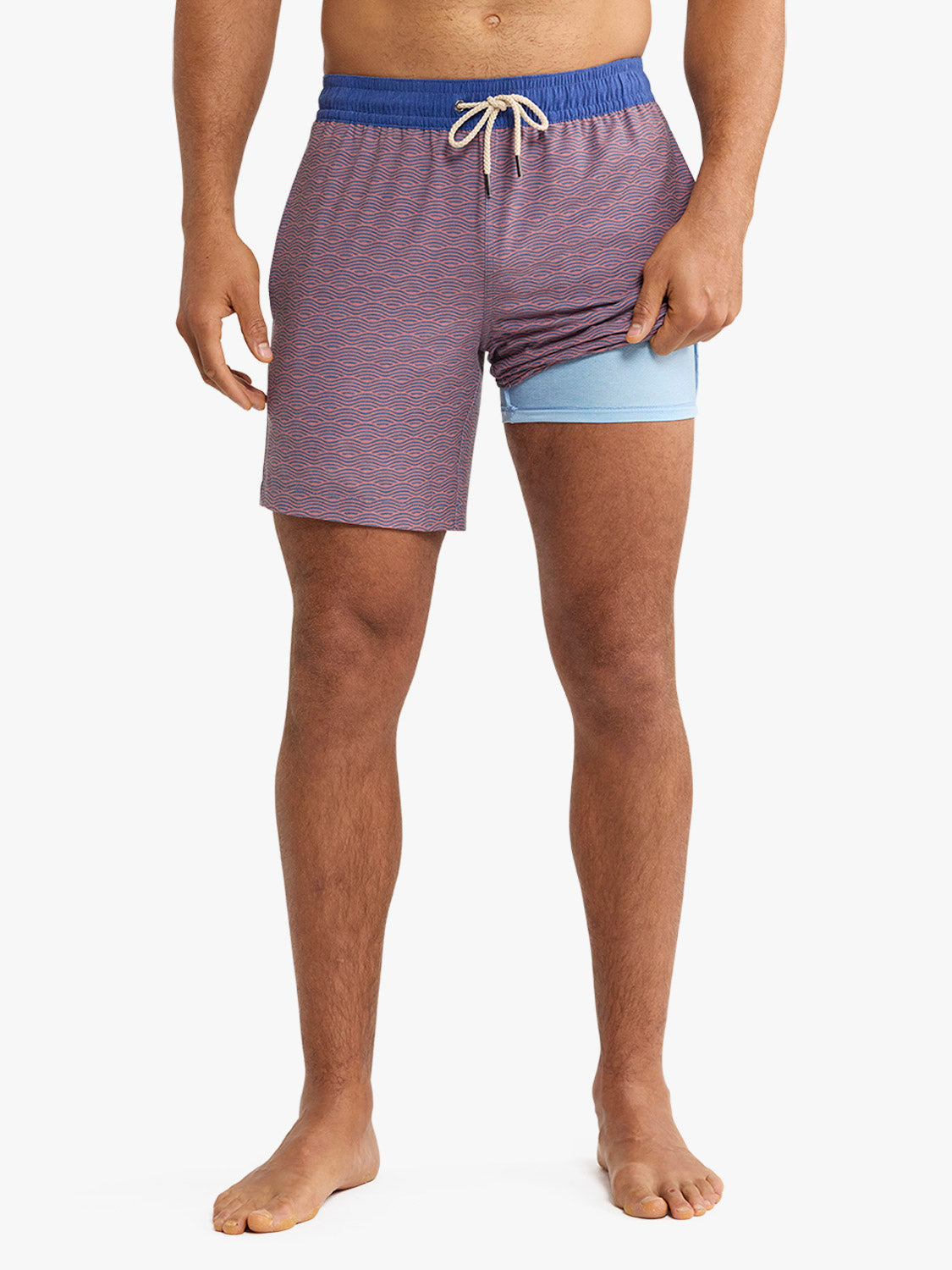 Man wearing purple swim trunks with red wave pattern and blue waistband with drawstring.