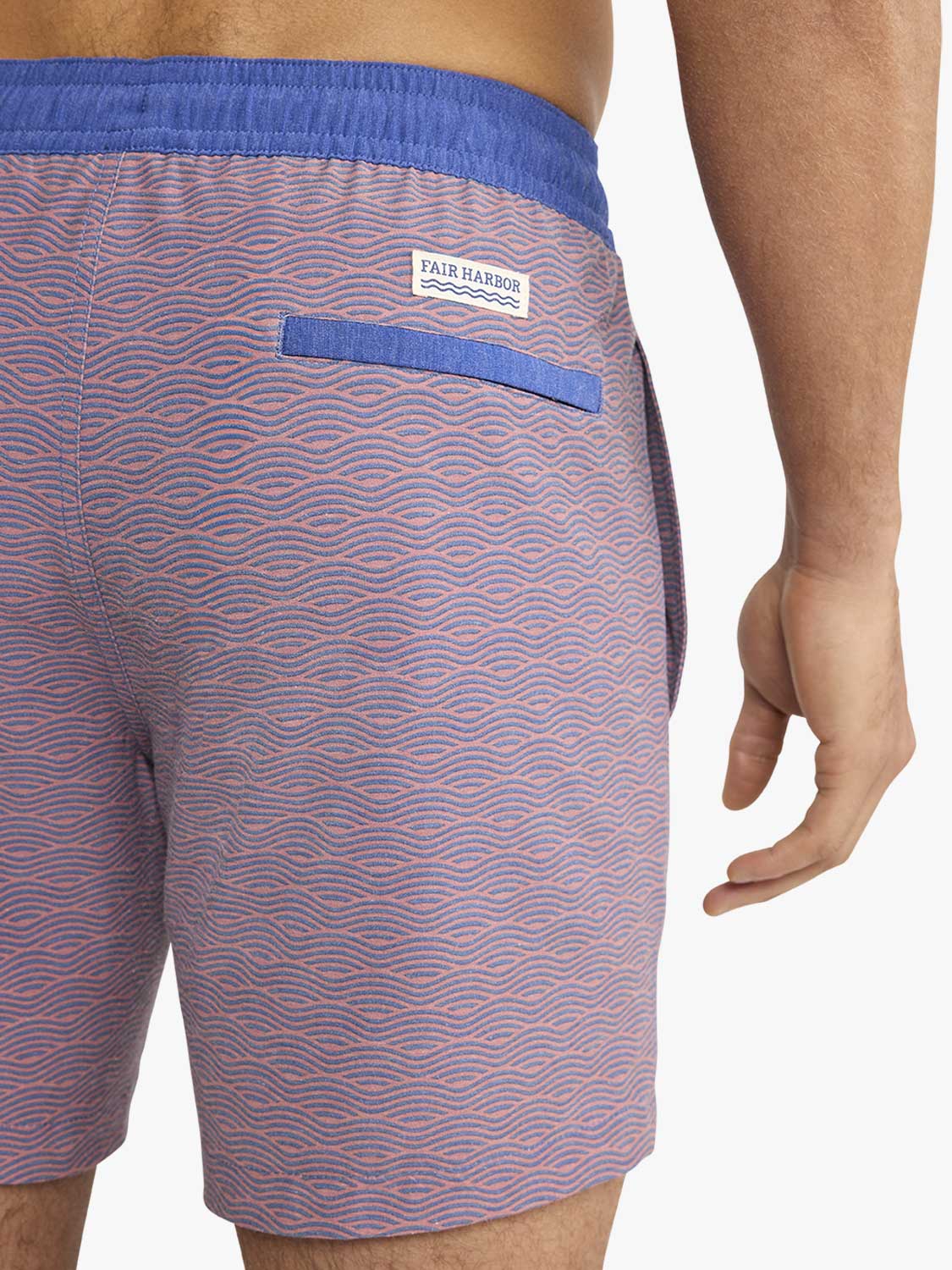 Red and blue wave-patterned swim trunk with blue waistband and back pocket detail.