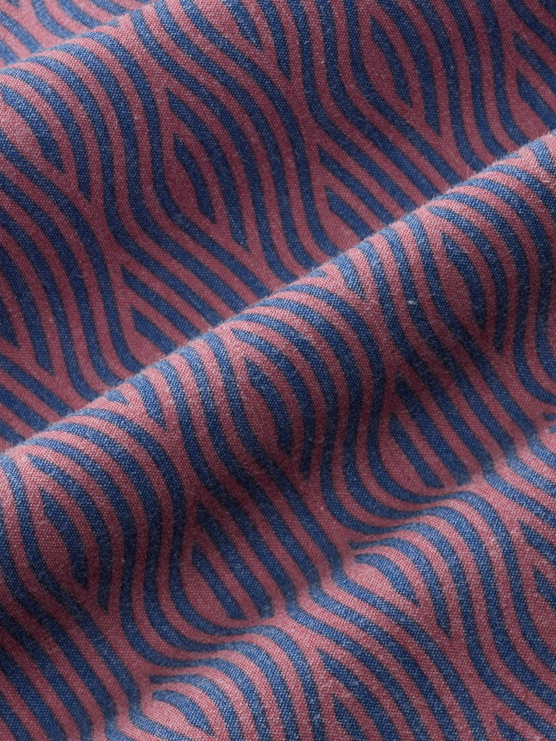 Red and blue wavy striped fabric with textured woven surface showing curved wave patterns.