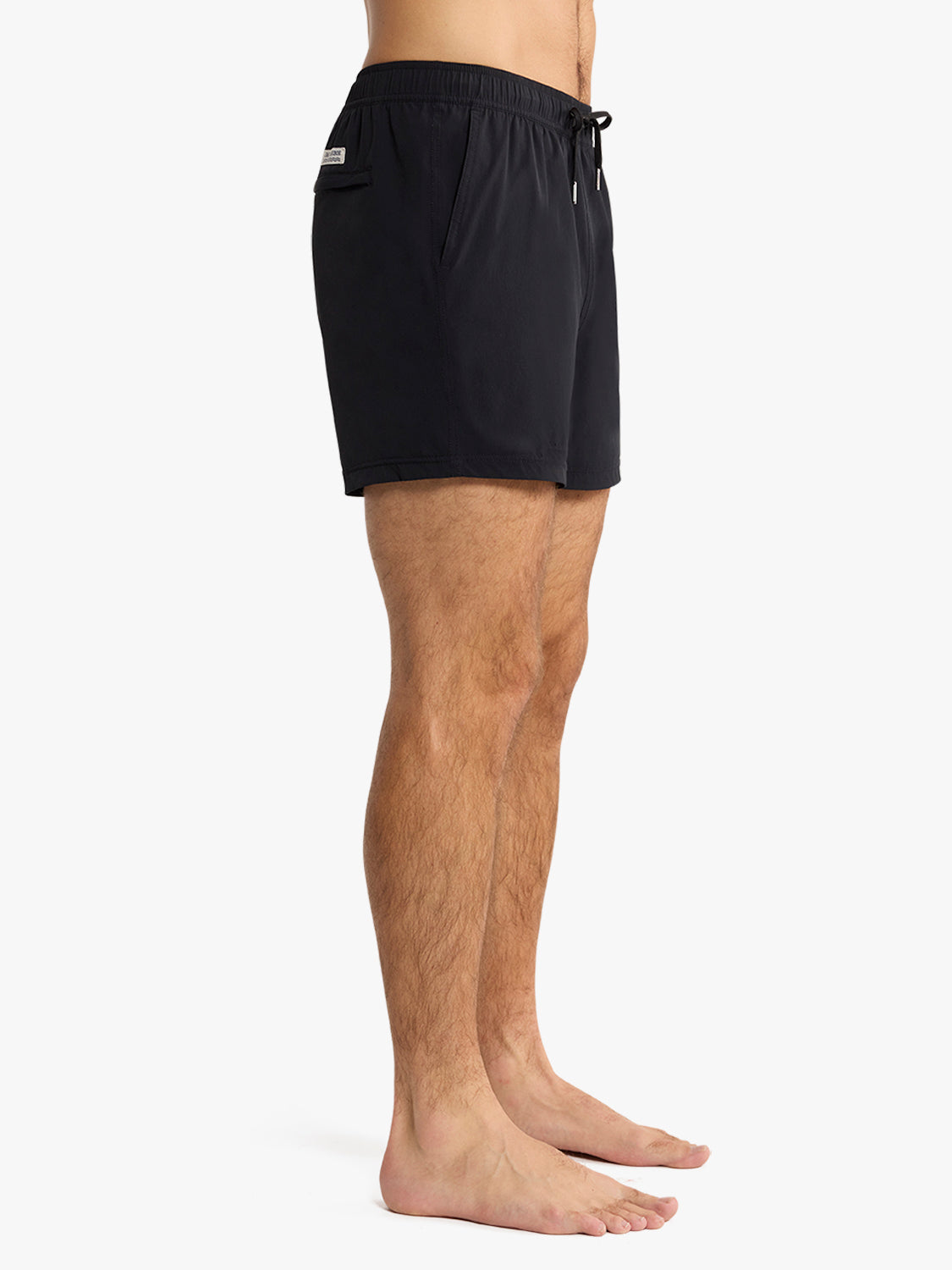 Black swim trunk with drawstring waistband and side pocket on man's body.