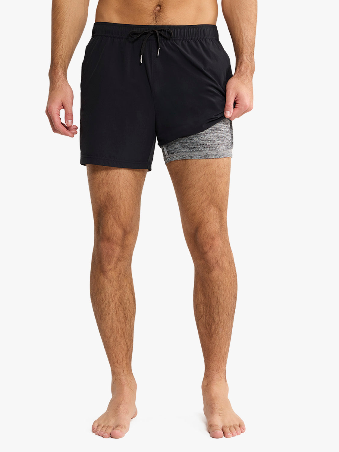 Man wearing black swim trunk with gray contrast inset and drawstring waistband.