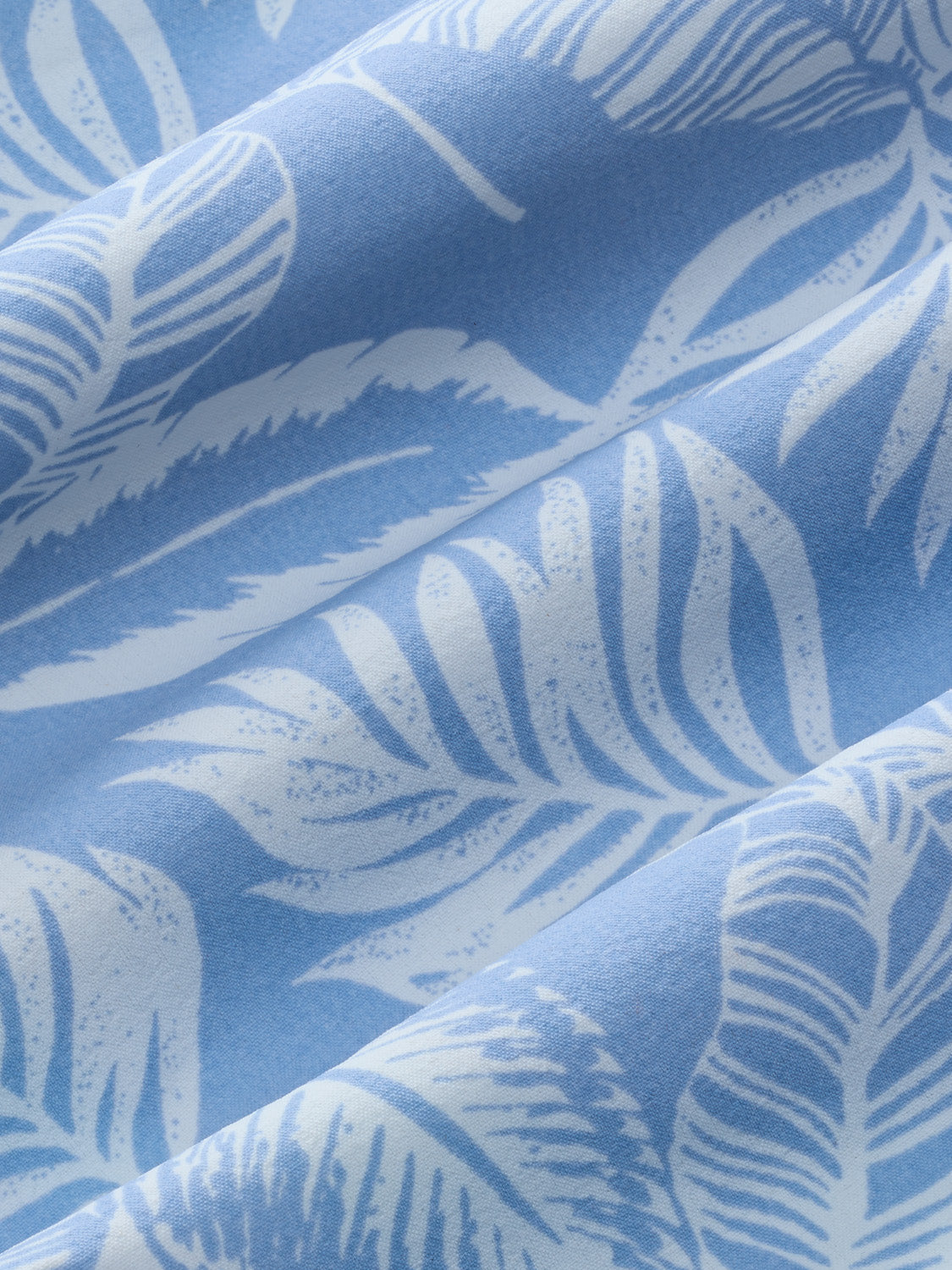 Sky blue fabric with white leaf patterns printed across textured folds.