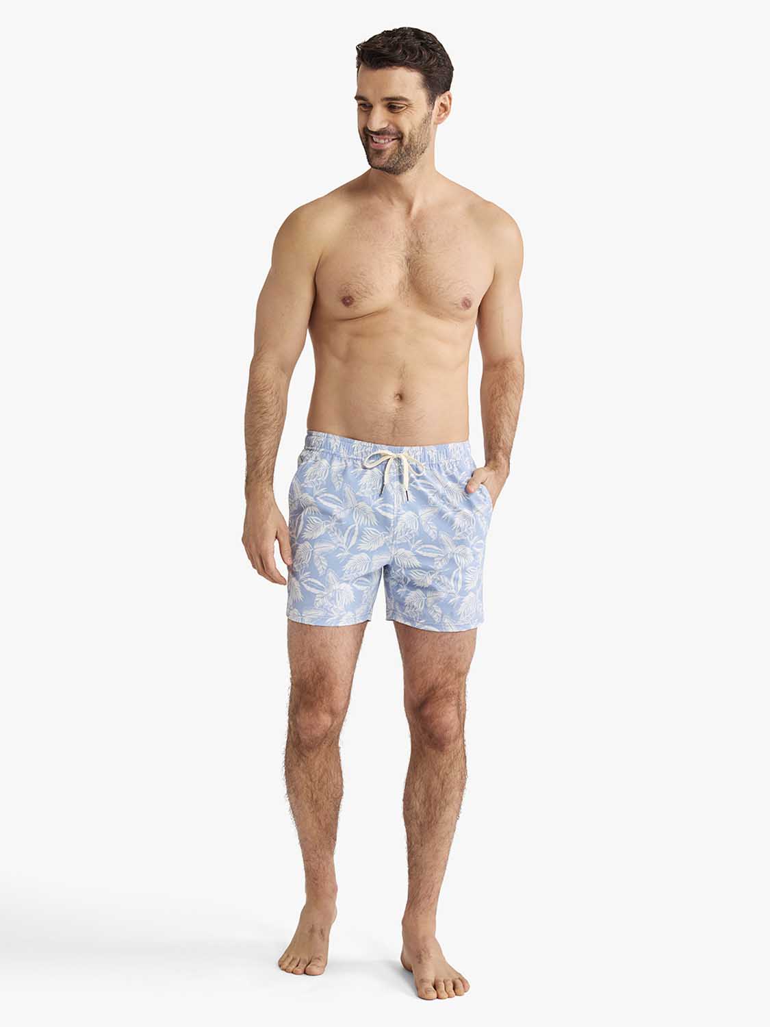 Man wearing sky blue swim shorts with white leaf pattern and drawstring waistband.