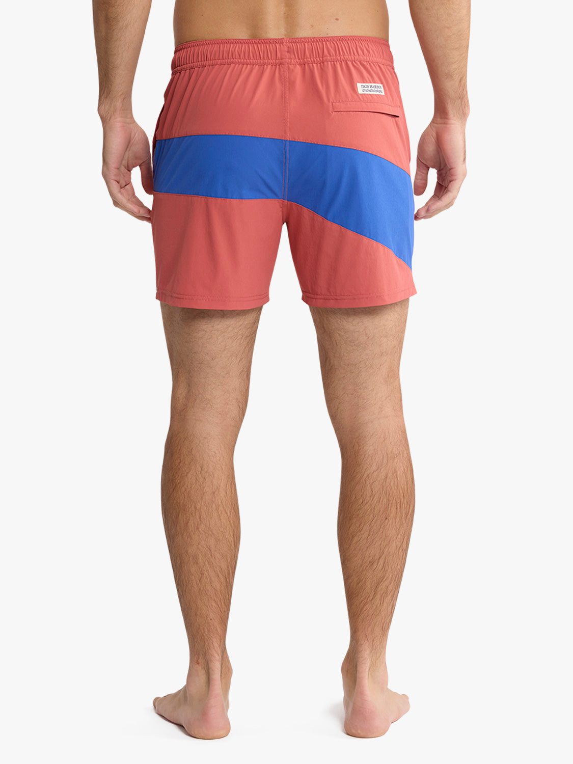 Man wearing red and blue colorblock swim trunks with back pocket visible.