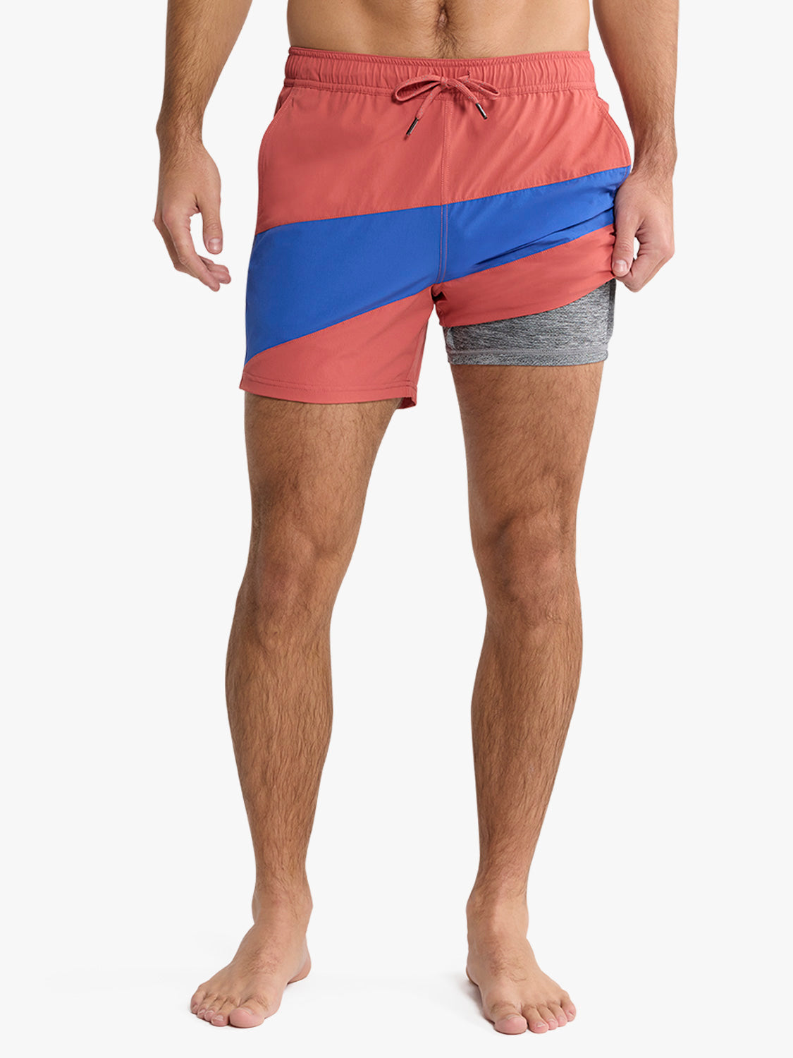 Man wearing red, blue, and gray colorblock swim trunks with a drawstring waist.