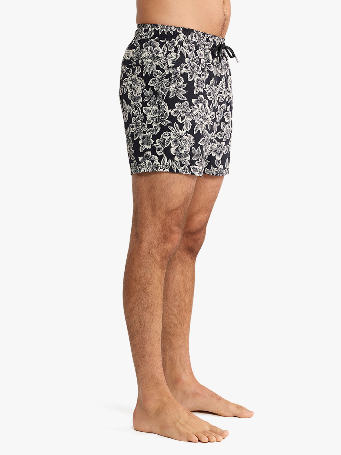 Black swim trunks with white hibiscus flower print and drawstring waistband.