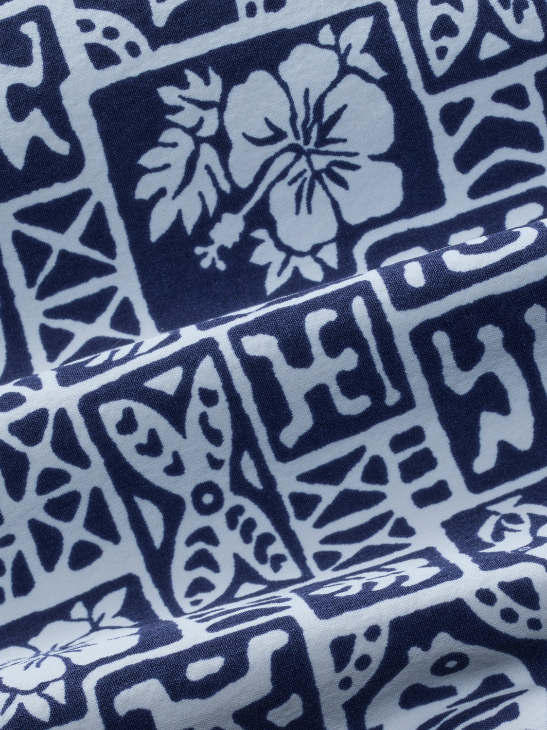 Navy and light blue fabric with repeating tile pattern featuring flowers and geometric shapes.