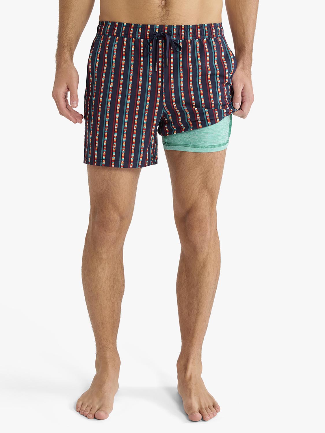 Man wearing navy swim trunks with red and blue vertical stripes and turquoise liner shorts.