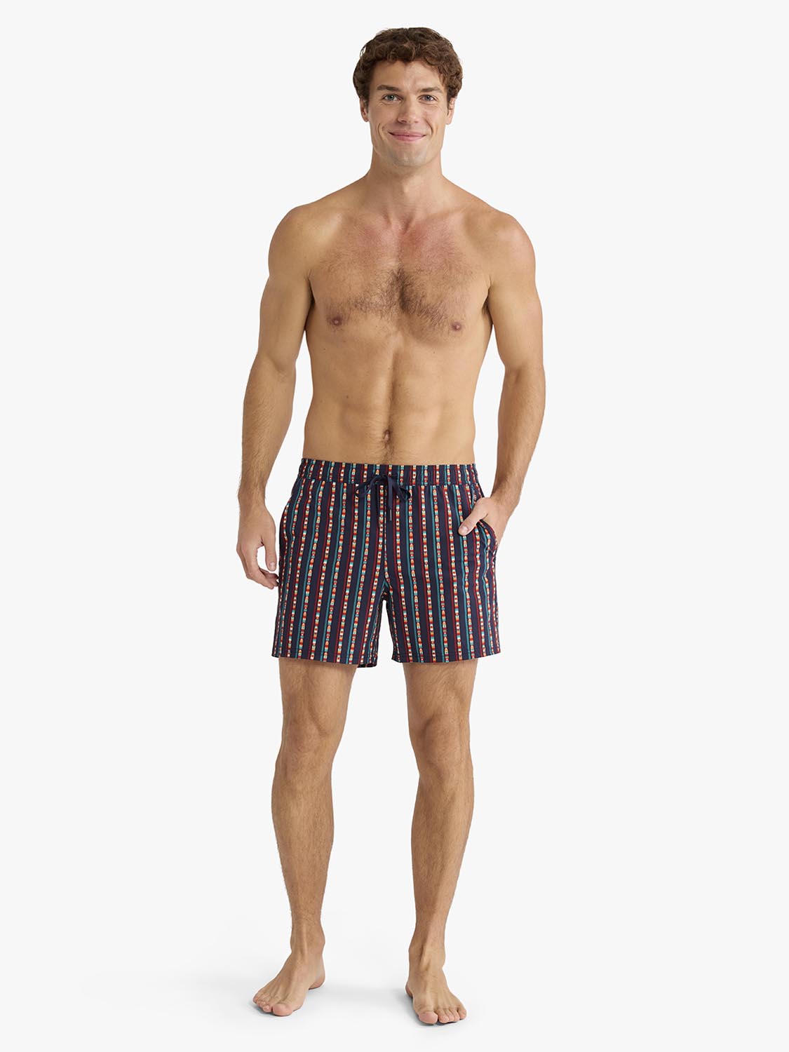 Man wearing navy swim trunks with red and white vertical stripe pattern standing against white background.
