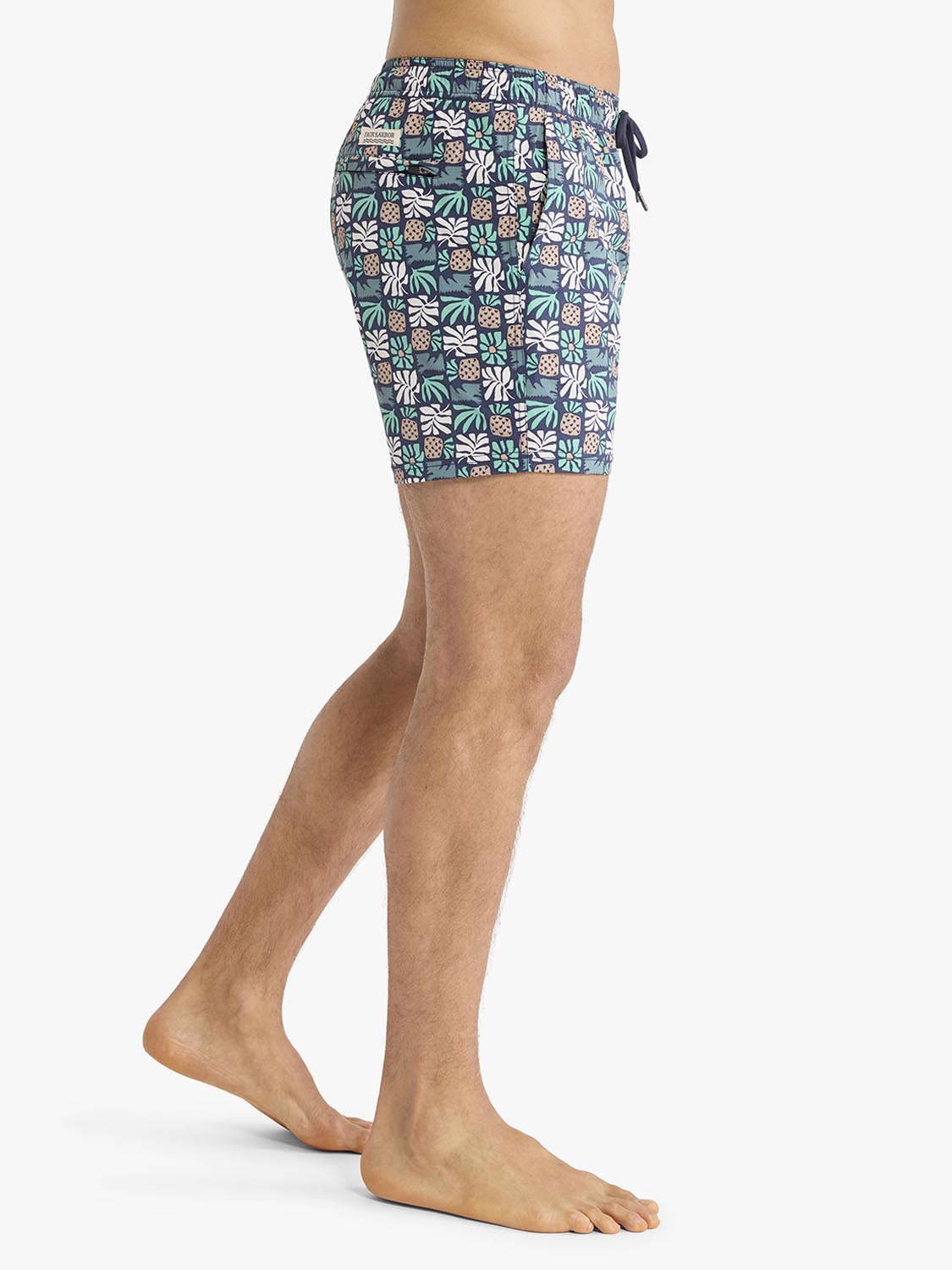 Men's swim shorts with navy base and multicolored palm tile pattern design featuring drawstring waistband.