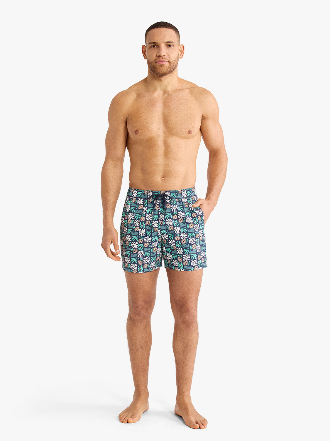 Man wearing navy swim shorts with palm tile pattern and drawstring waistband.