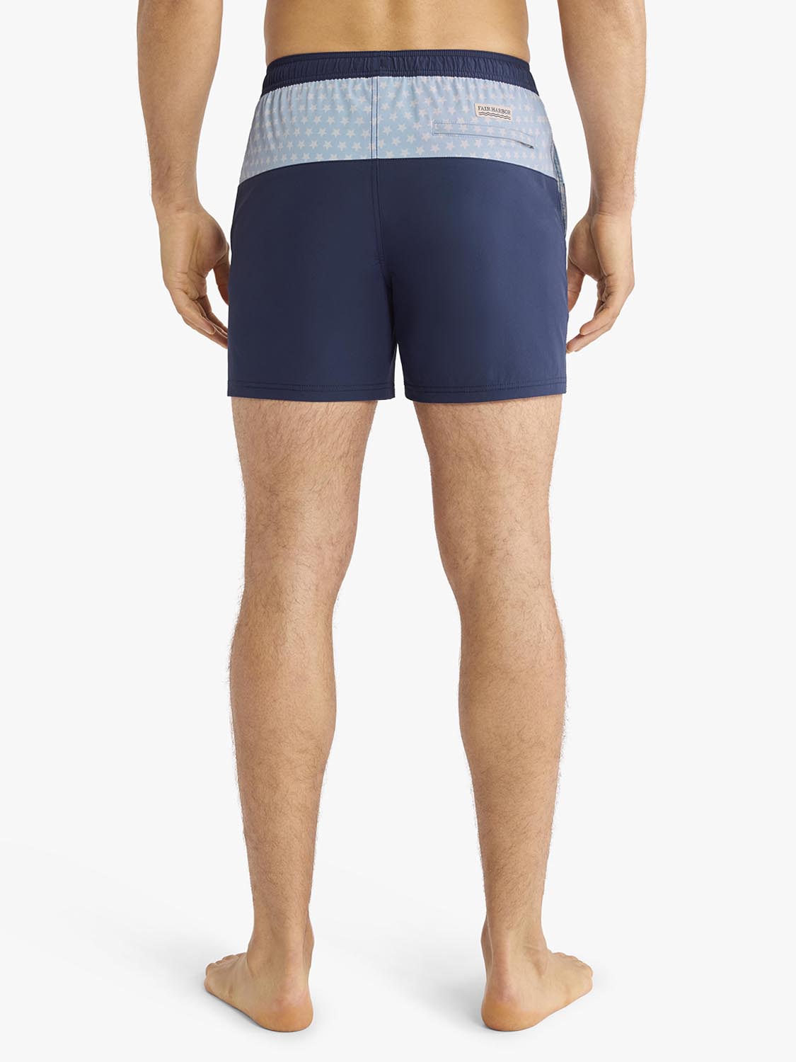 Man wearing navy swim trunks with light blue patterned waistband, shown from behind.