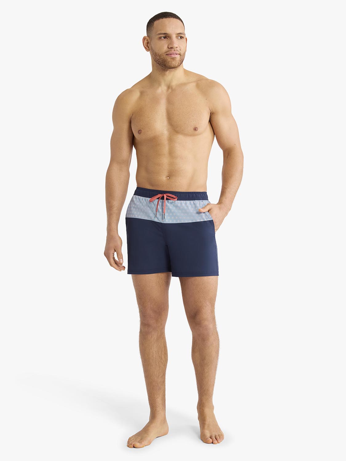 Man wearing navy and light blue color-block swim trunk with red drawstring detail.