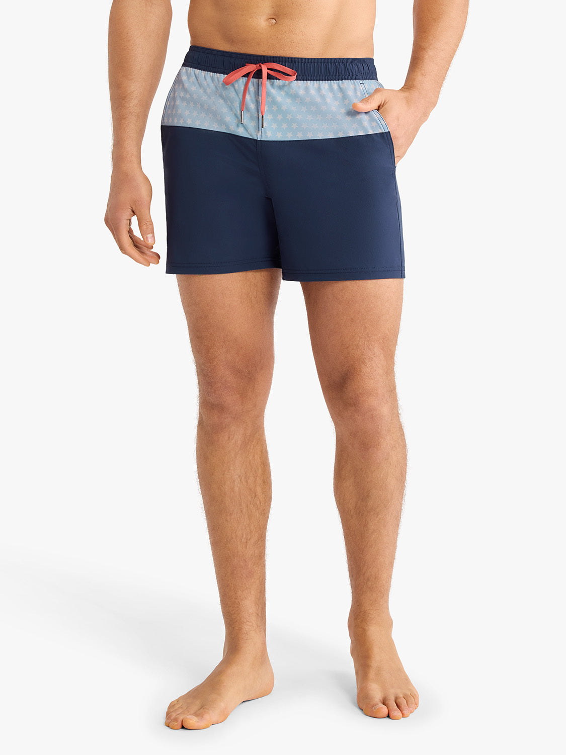 Man wearing navy swim trunks with light blue patterned waistband and coral drawstring.