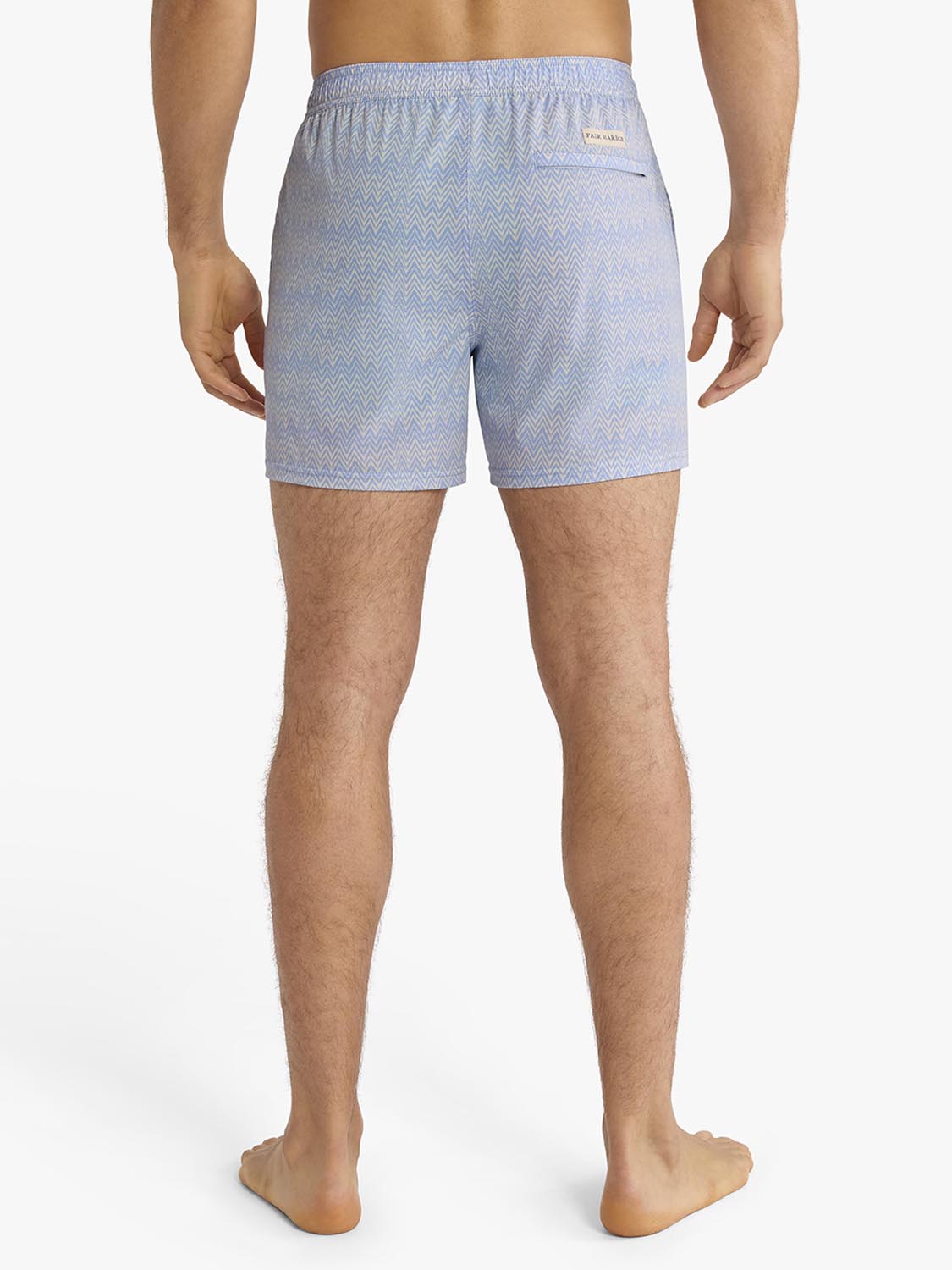 Man wearing light blue textured swim shorts with a chevron pattern viewed from behind.